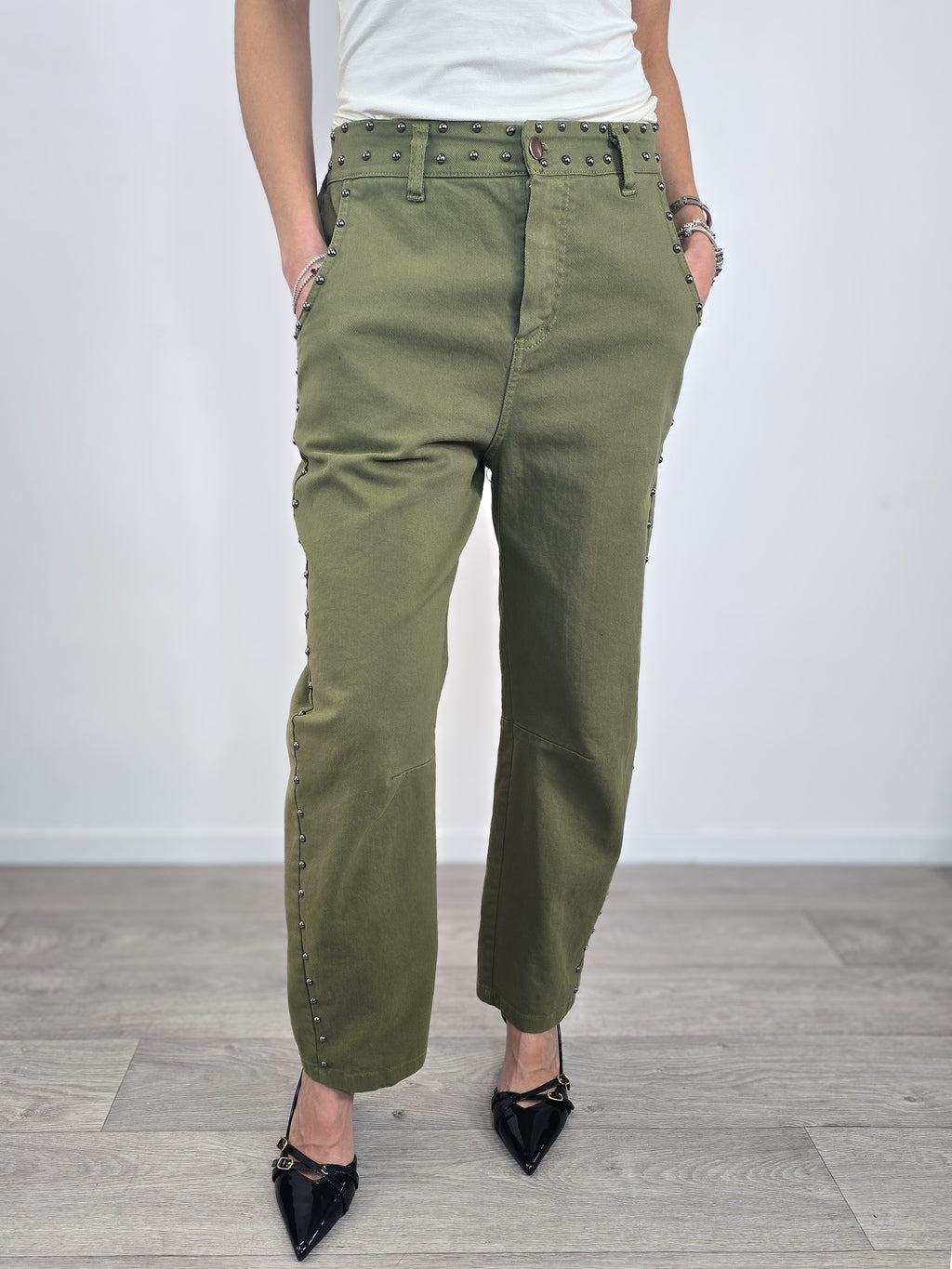 Pantaloni Kontatto in cotone verde militare dal taglio baloon, caratterizzati da profili con borchie metalliche e abbinati a scarpe décolleté nere.
