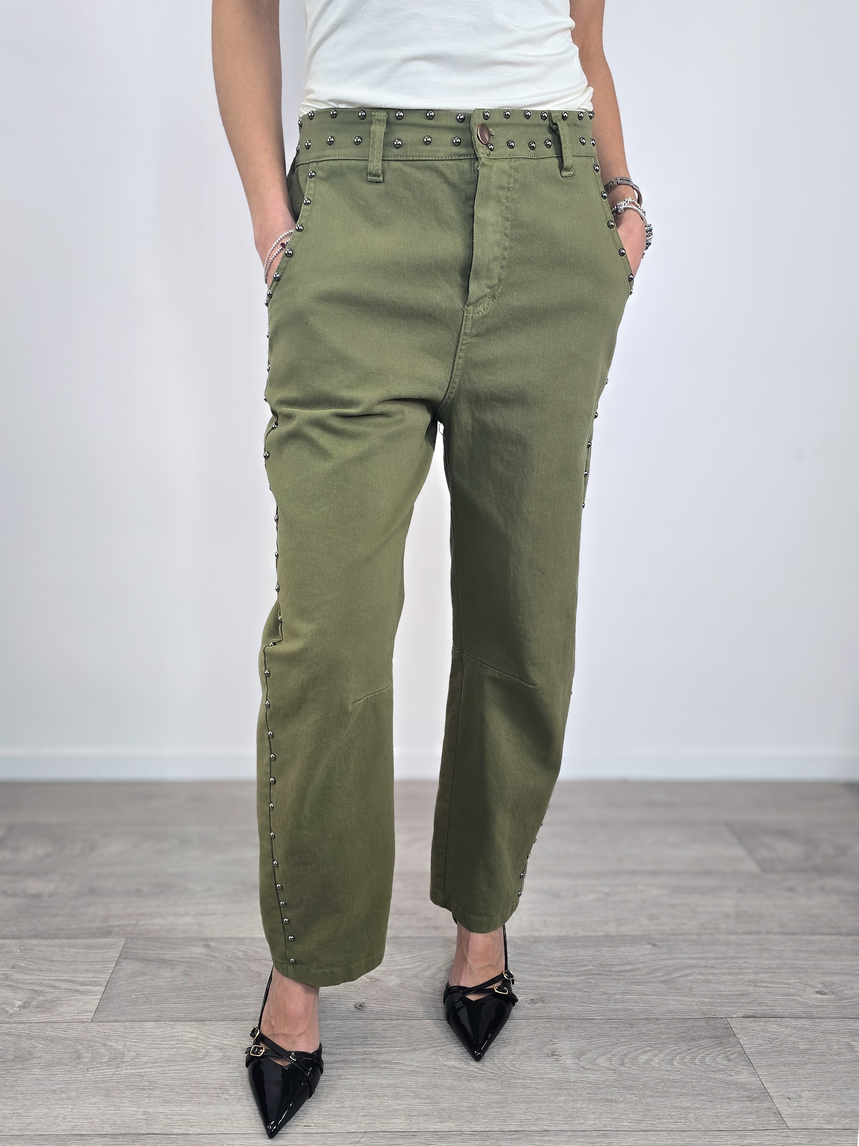 Pantaloni Kontatto in cotone verde militare dal taglio baloon, caratterizzati da profili con borchie metalliche e abbinati a scarpe décolleté nere.