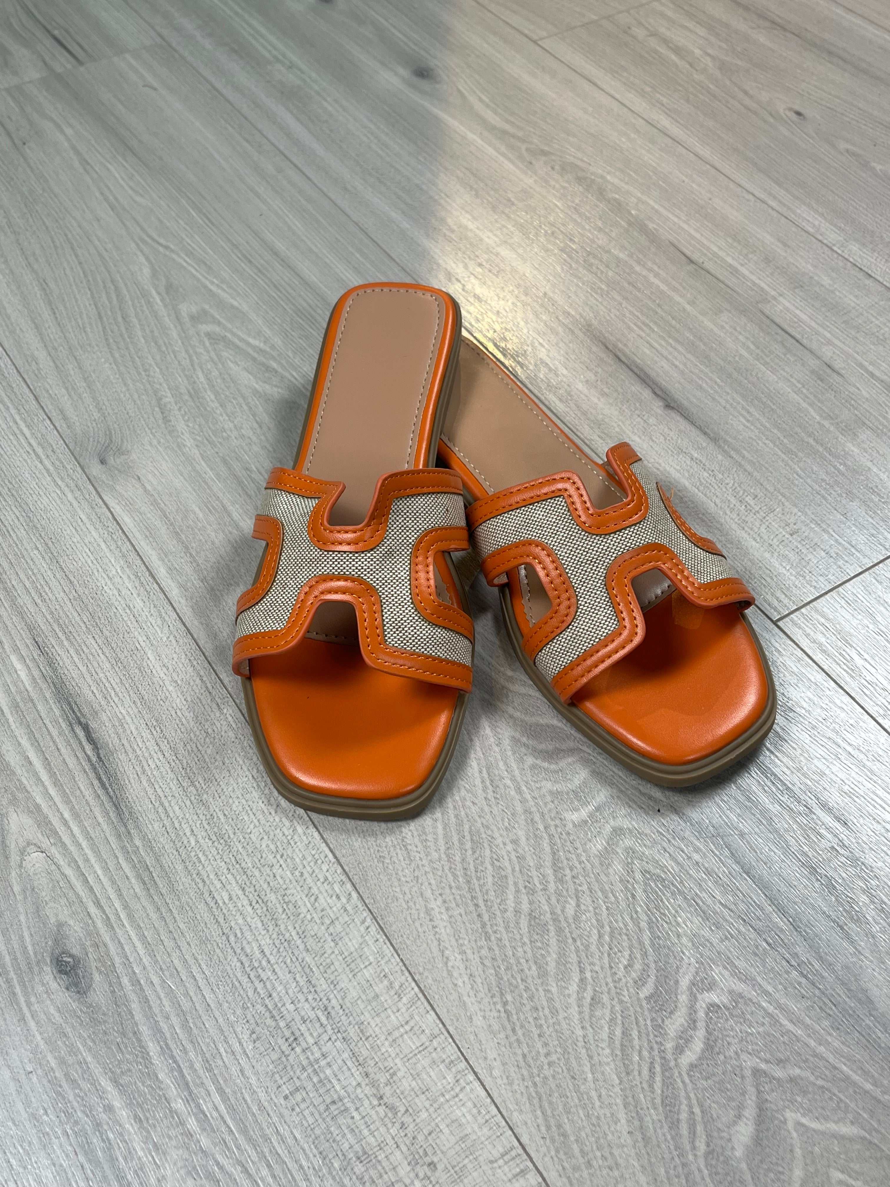 Ciabattina Kelly Arancio orange flat narrow sole sandals on wooden floor
