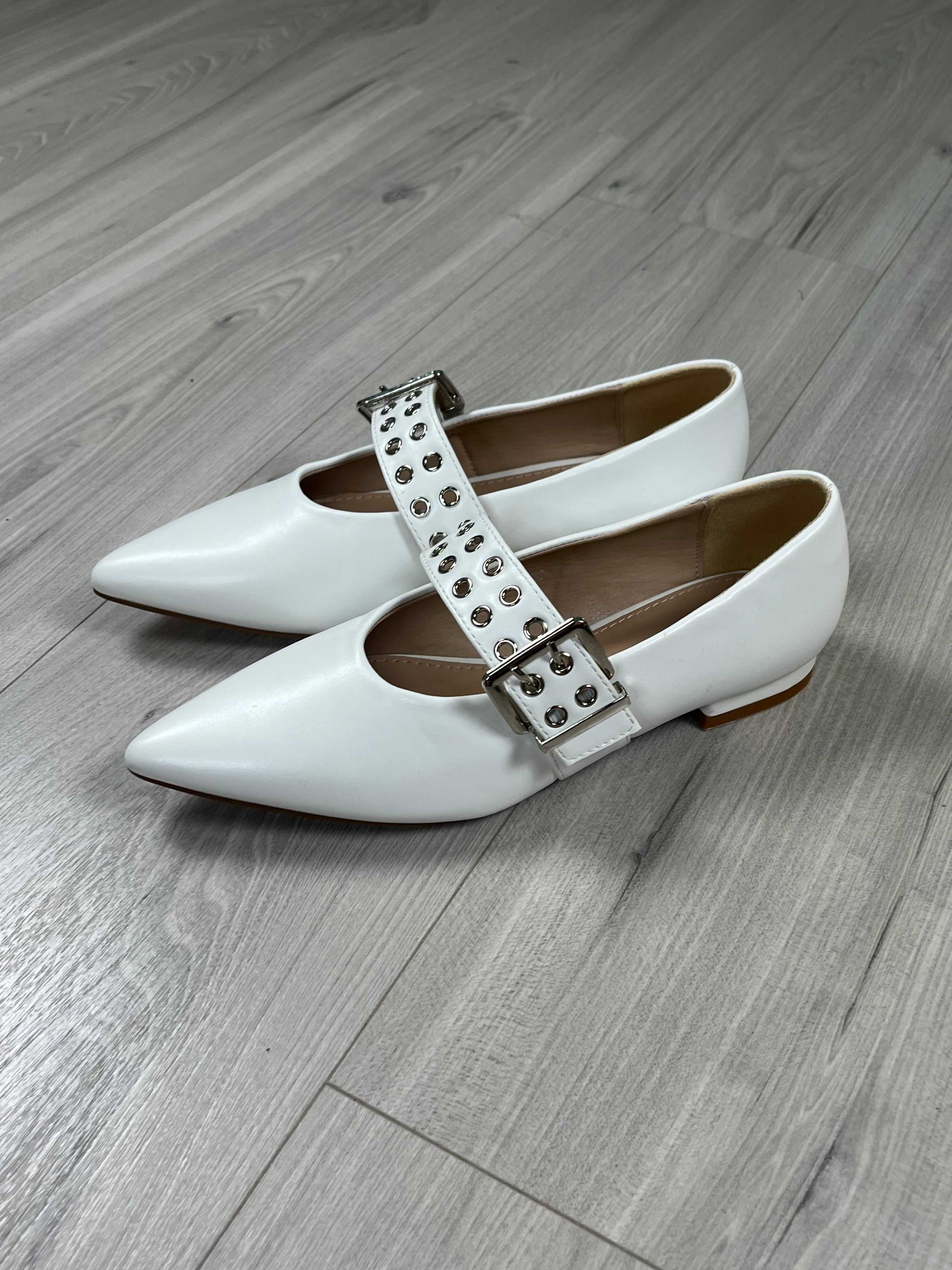 Ballerina a punta bianca con cinghietta regolabile e calzata regolare su pavimento in legno