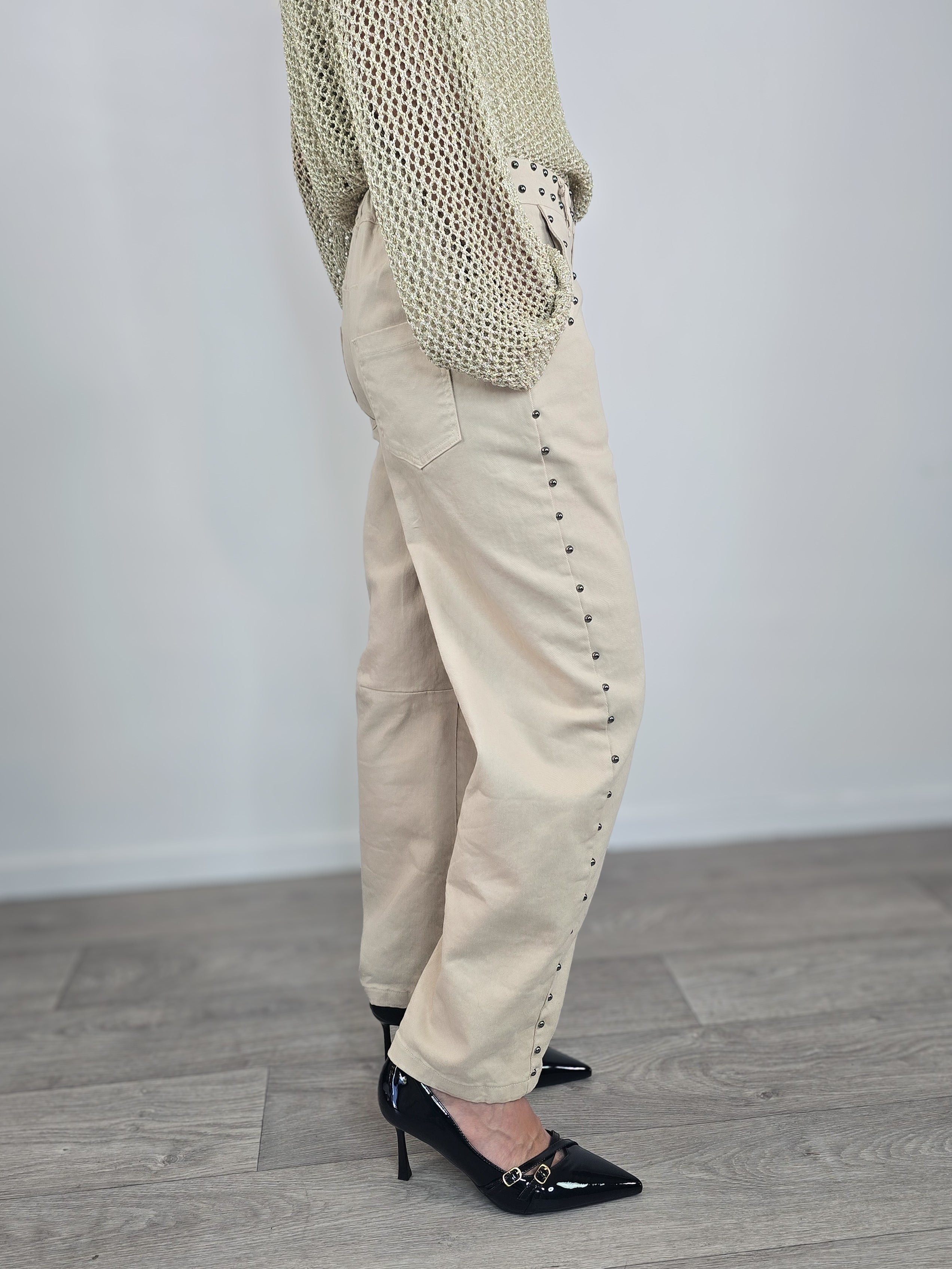 Pantaloni Kontatto modello "baloon" color beige con borchie applicate lungo i fianchi, le tasche e la vita, abbinati a décolleté nere a punta.