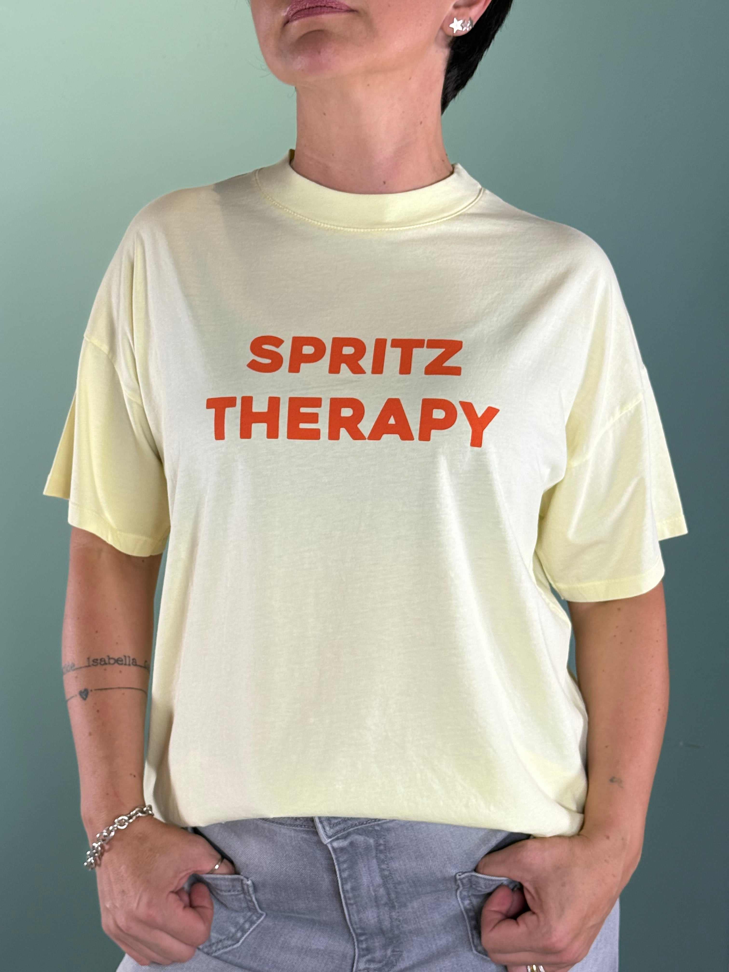 Woman wearing yellow cotton T-shirt Spritz Therapy with orange print and over fit