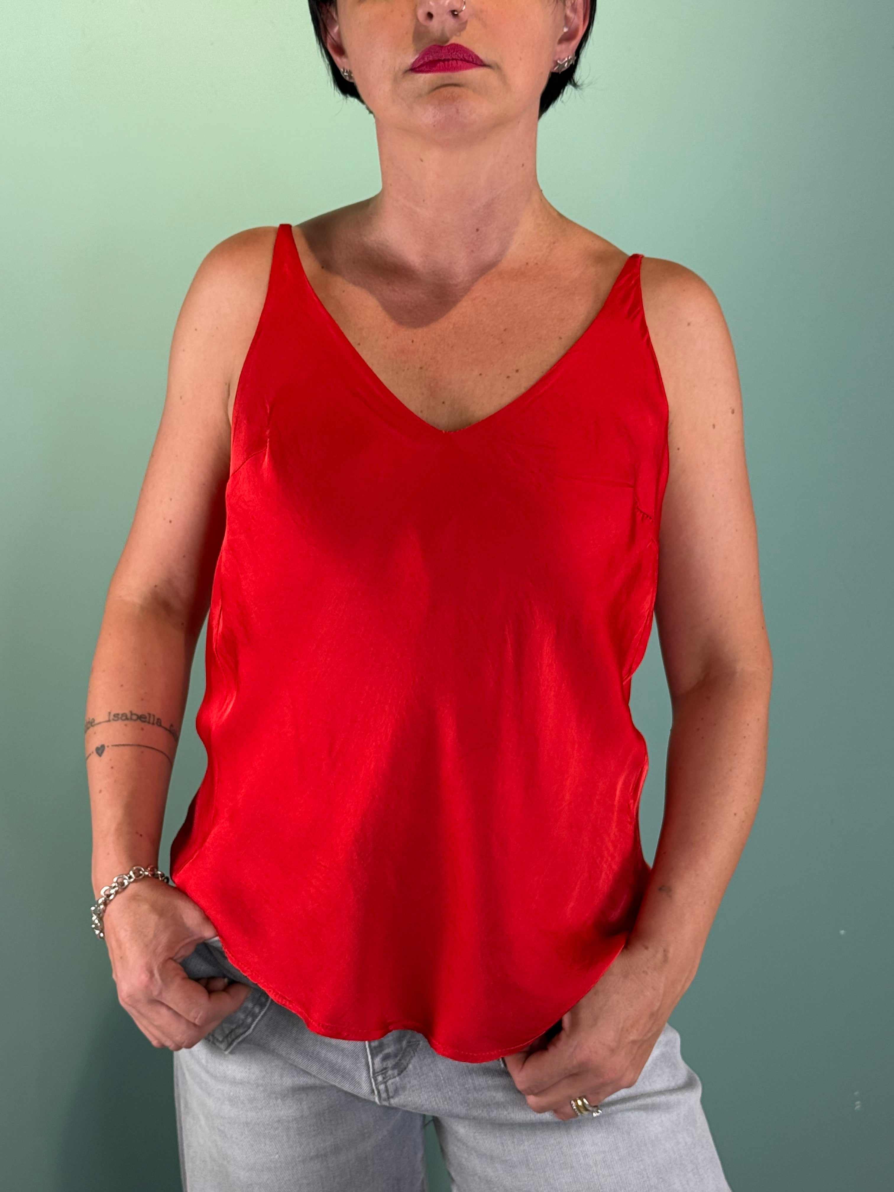 Top a V Rosso in tessuto lucido con spalline sottili e fit regolare indossato da donna