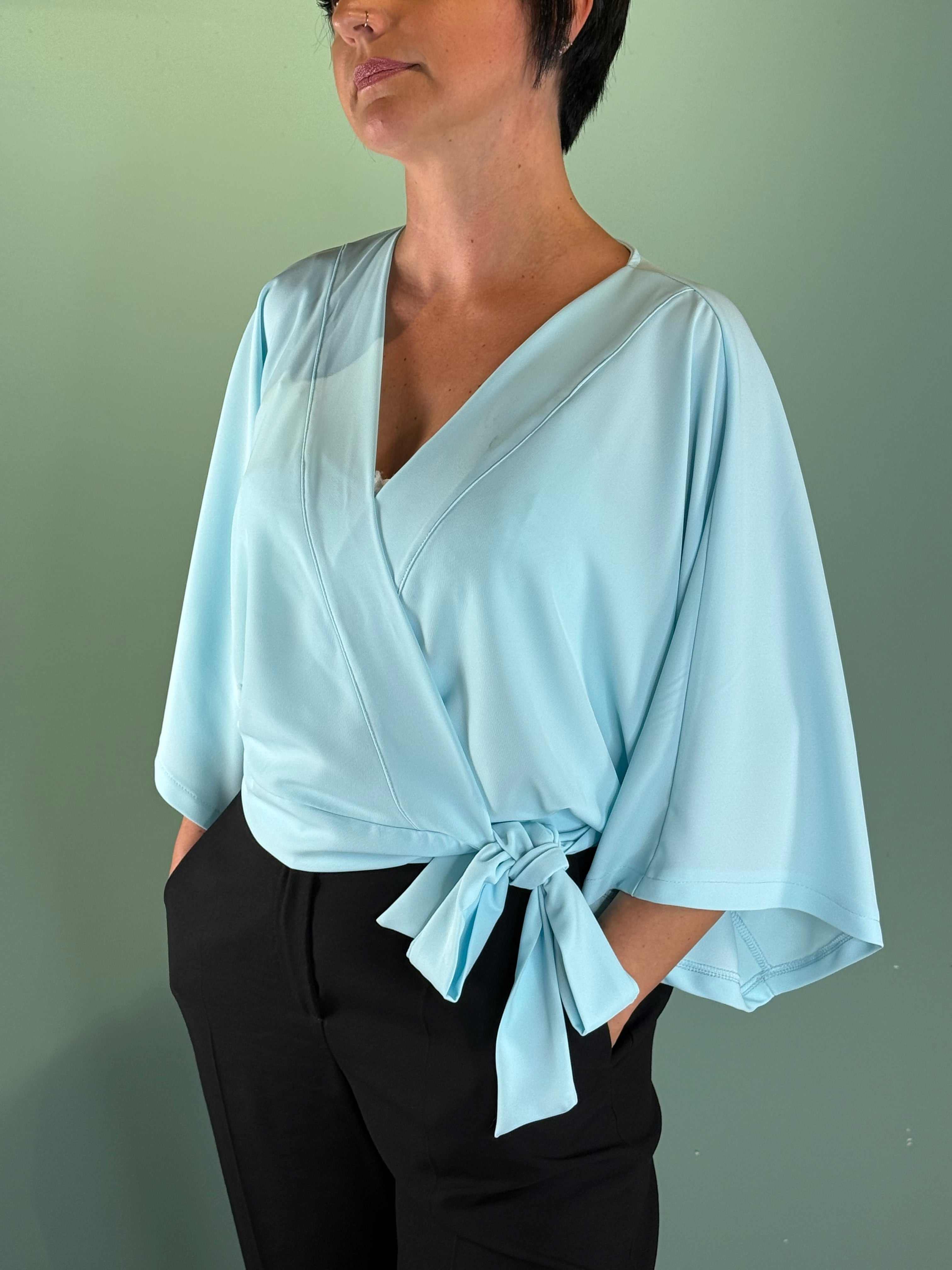 Woman wearing light blue Scaldacuore Barbie Saiph wrap top with bow detail and soft fit