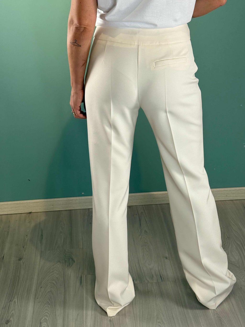 Back view of woman wearing Pantalone Vanilla Please beige flare pants in polyester and elastane blend