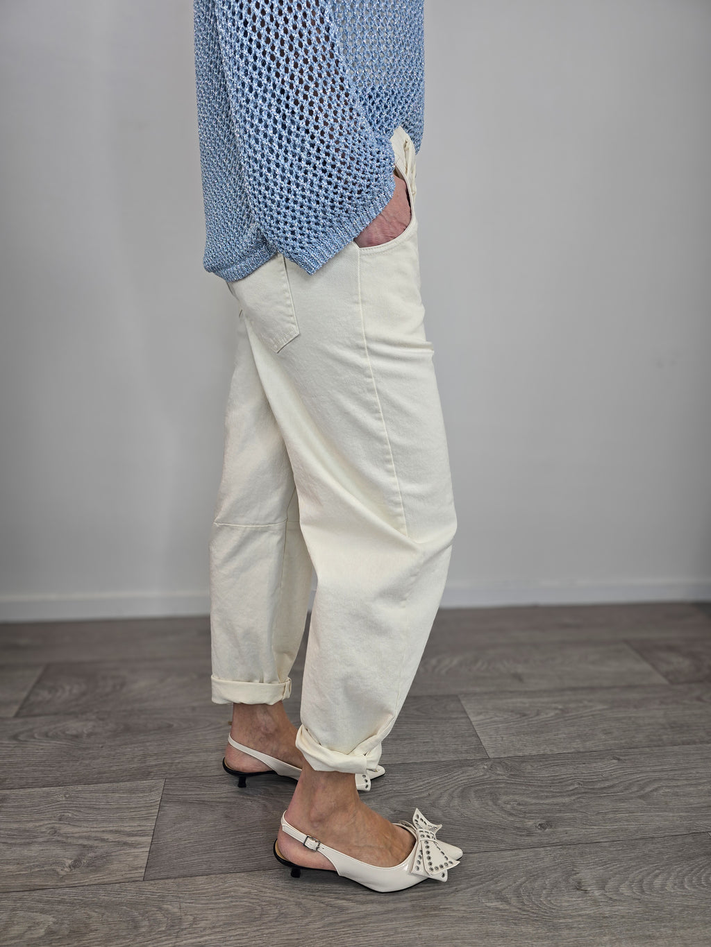 Pantaloni Kontatto modello barrel color avorio dal taglio curvo, indossati con risvolto alla caviglia e décolleté con fiocco.