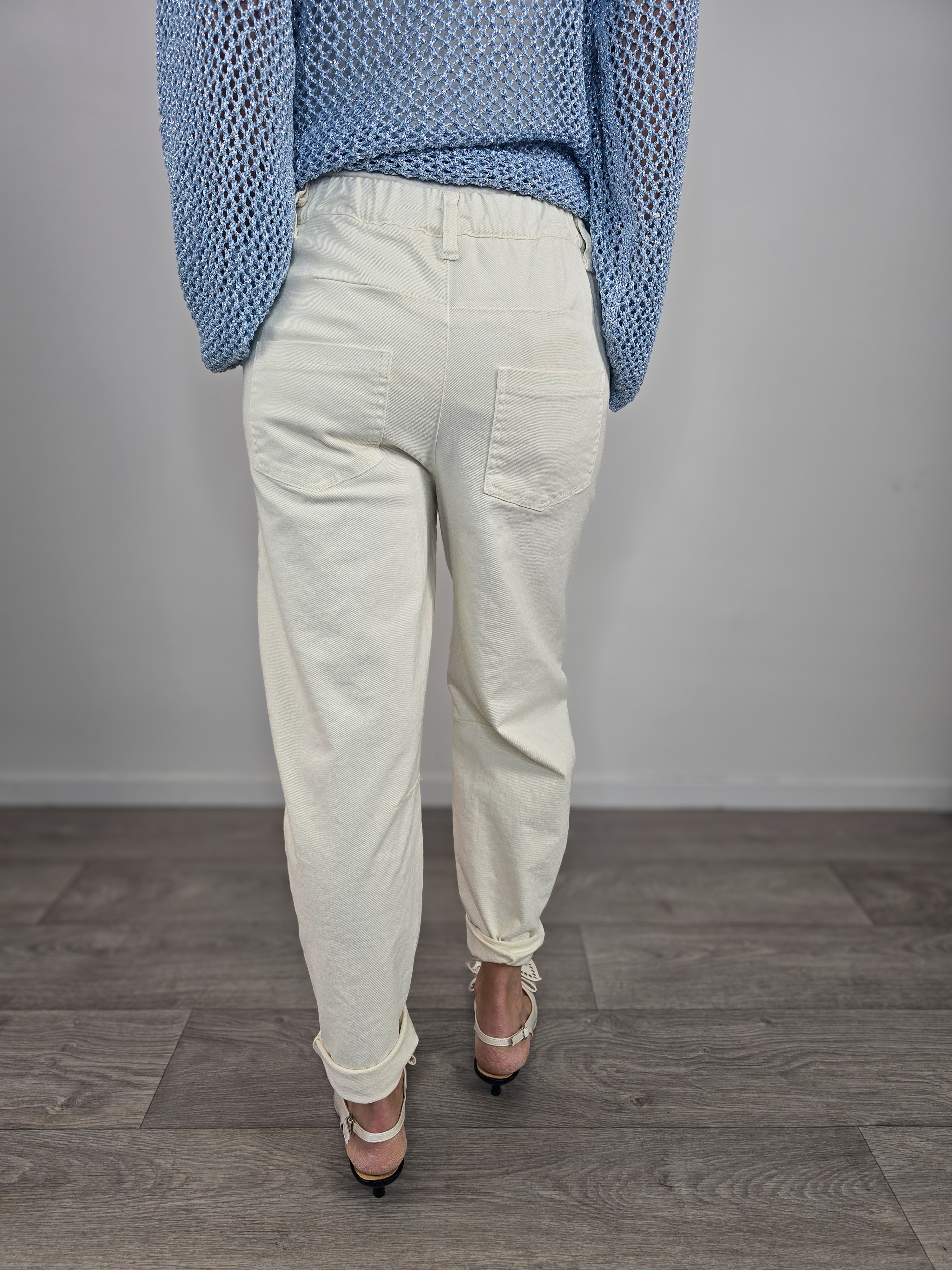 Pantaloni Kontatto modello barrel color avorio dal taglio curvo, indossati con risvolto alla caviglia e décolleté con fiocco. Back