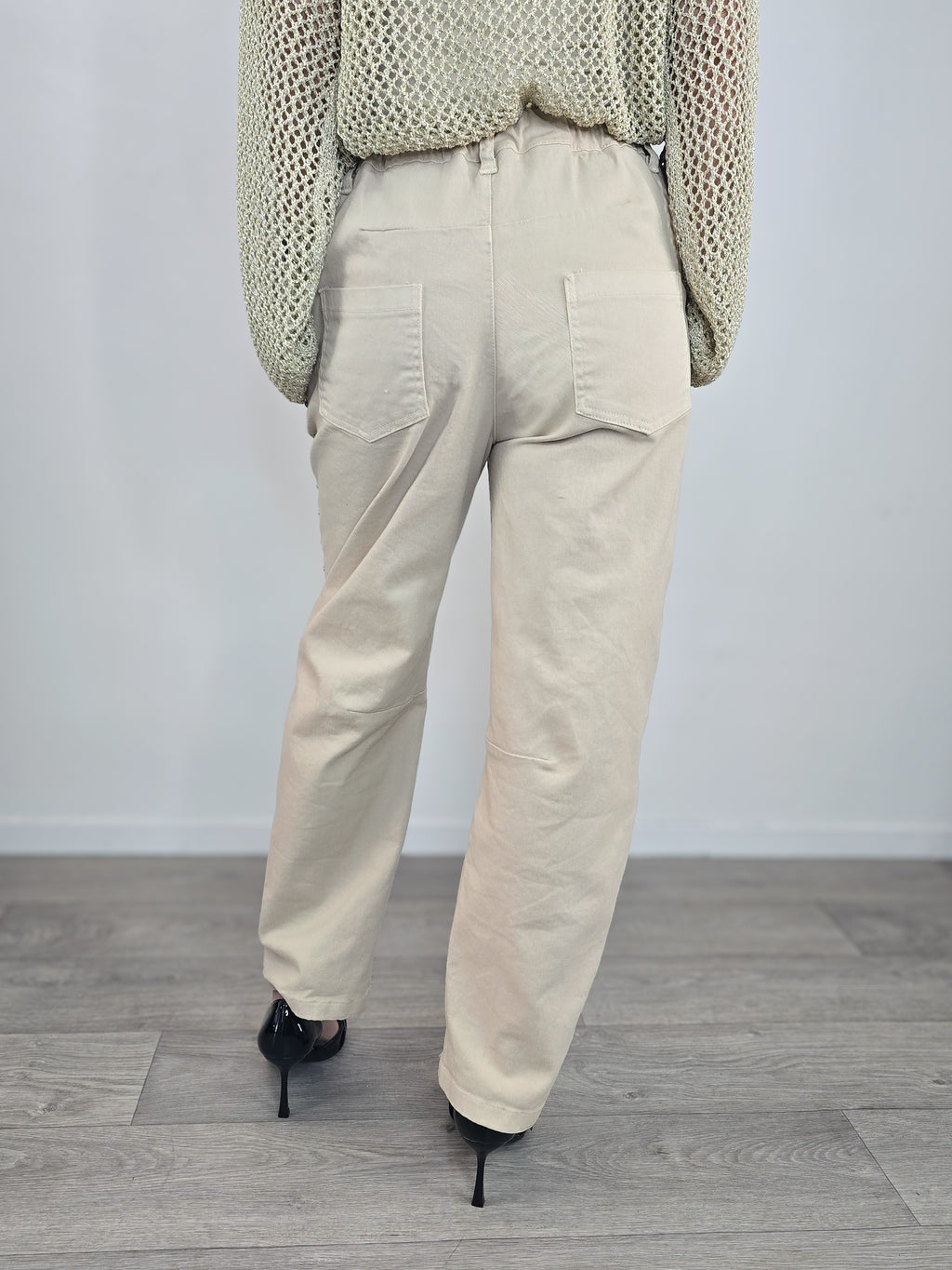 Pantaloni Kontatto modello "baloon" color beige con borchie applicate lungo i fianchi, le tasche e la vita, abbinati a décolleté nere a punta.