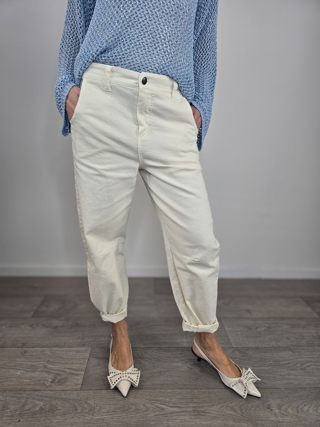Pantaloni Kontatto modello barrel color avorio dal taglio curvo, indossati con risvolto alla caviglia e décolleté con fiocco.