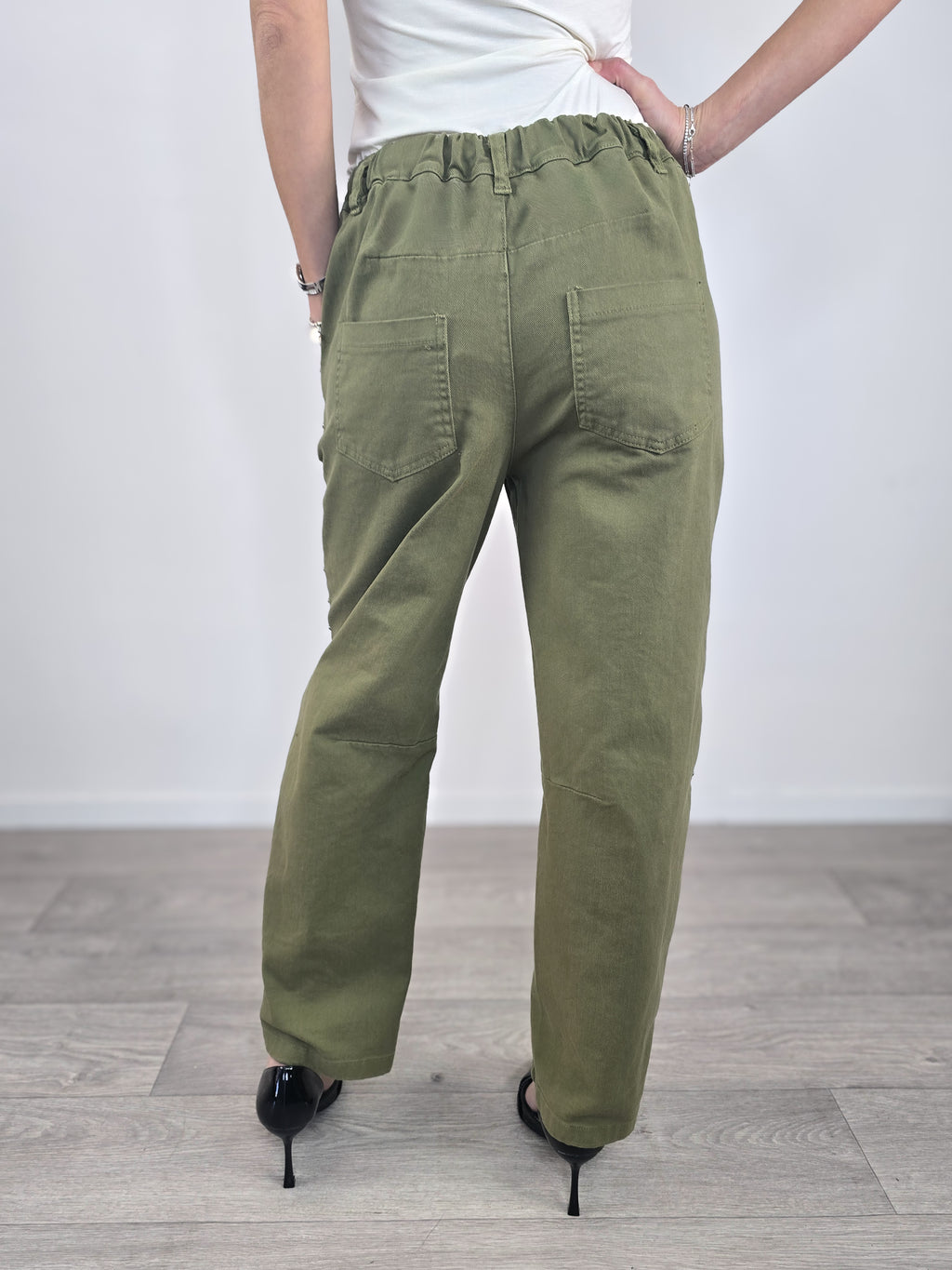 Pantaloni Kontatto in cotone verde militare dal taglio baloon, caratterizzati da profili con borchie metalliche e abbinati a scarpe décolleté nere.