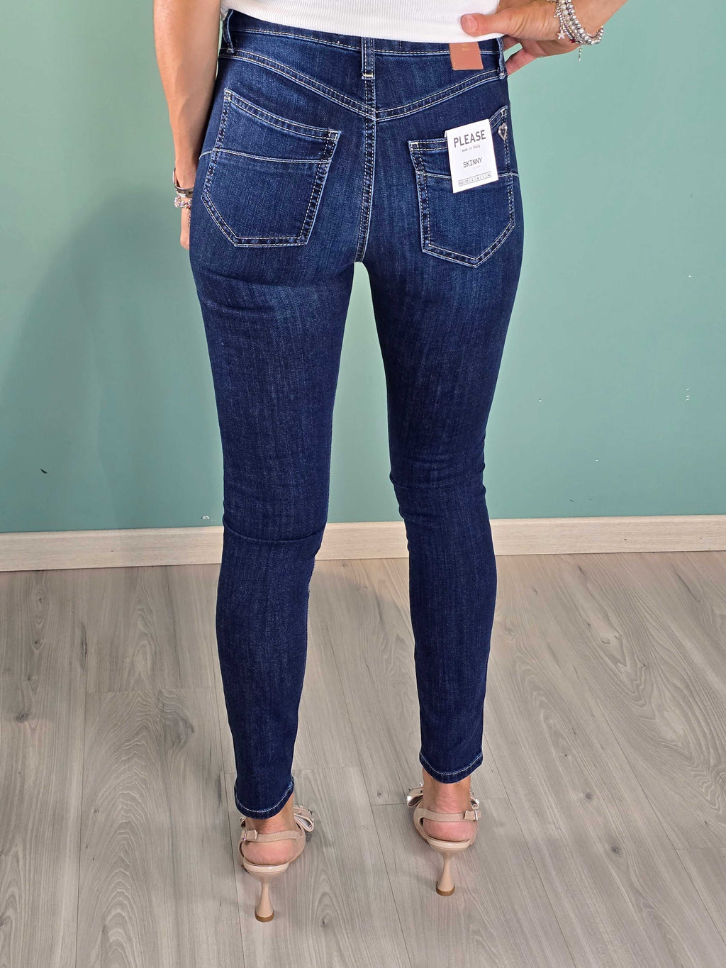 Back view of woman wearing dark blue denim skinny jeans with regular fit and label on back pocket