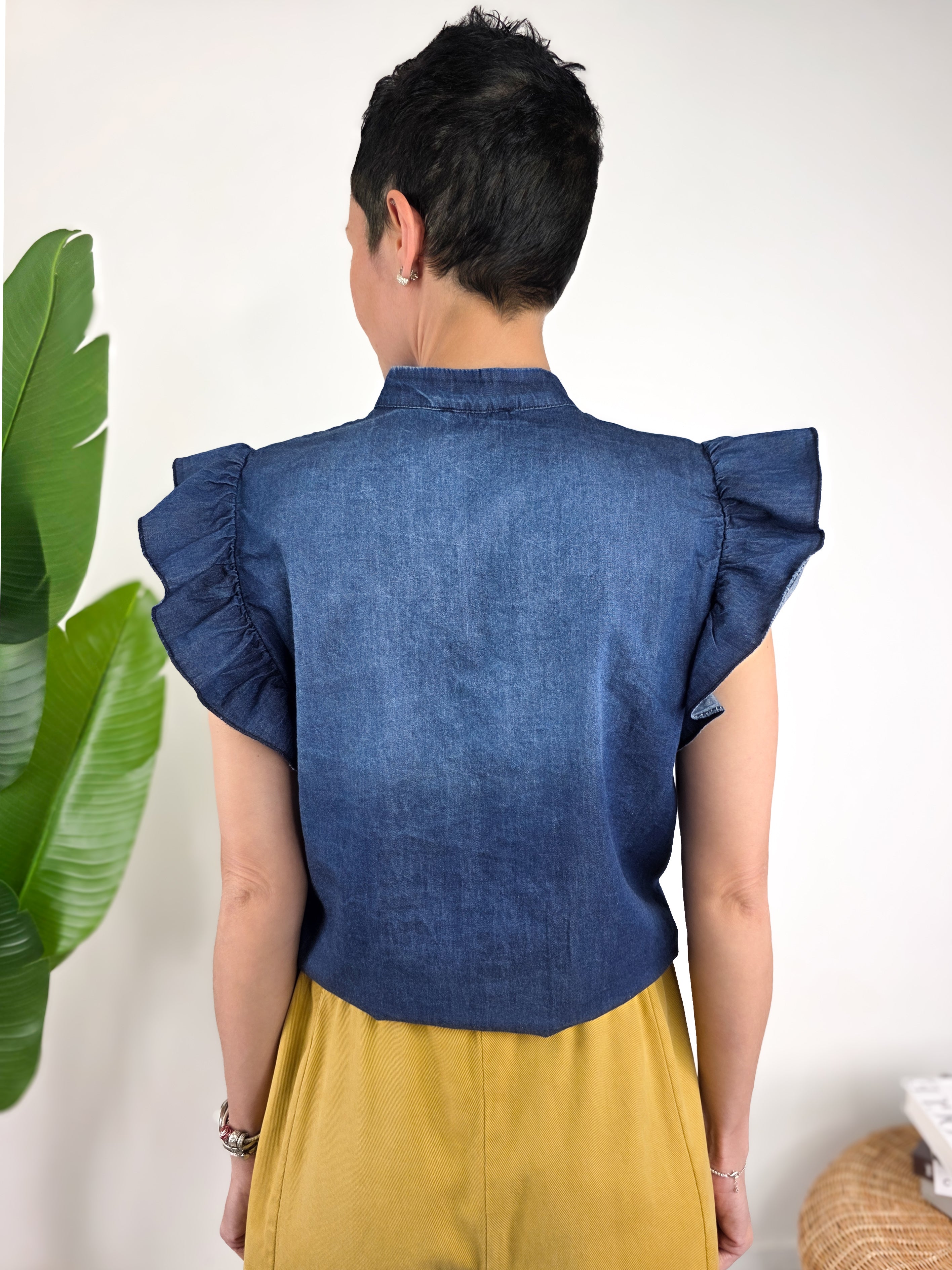 Dettaglio schiena della camicetta Susy Mix  in tessuto chambray blu con bottoncini frontali e maniche ad aletta