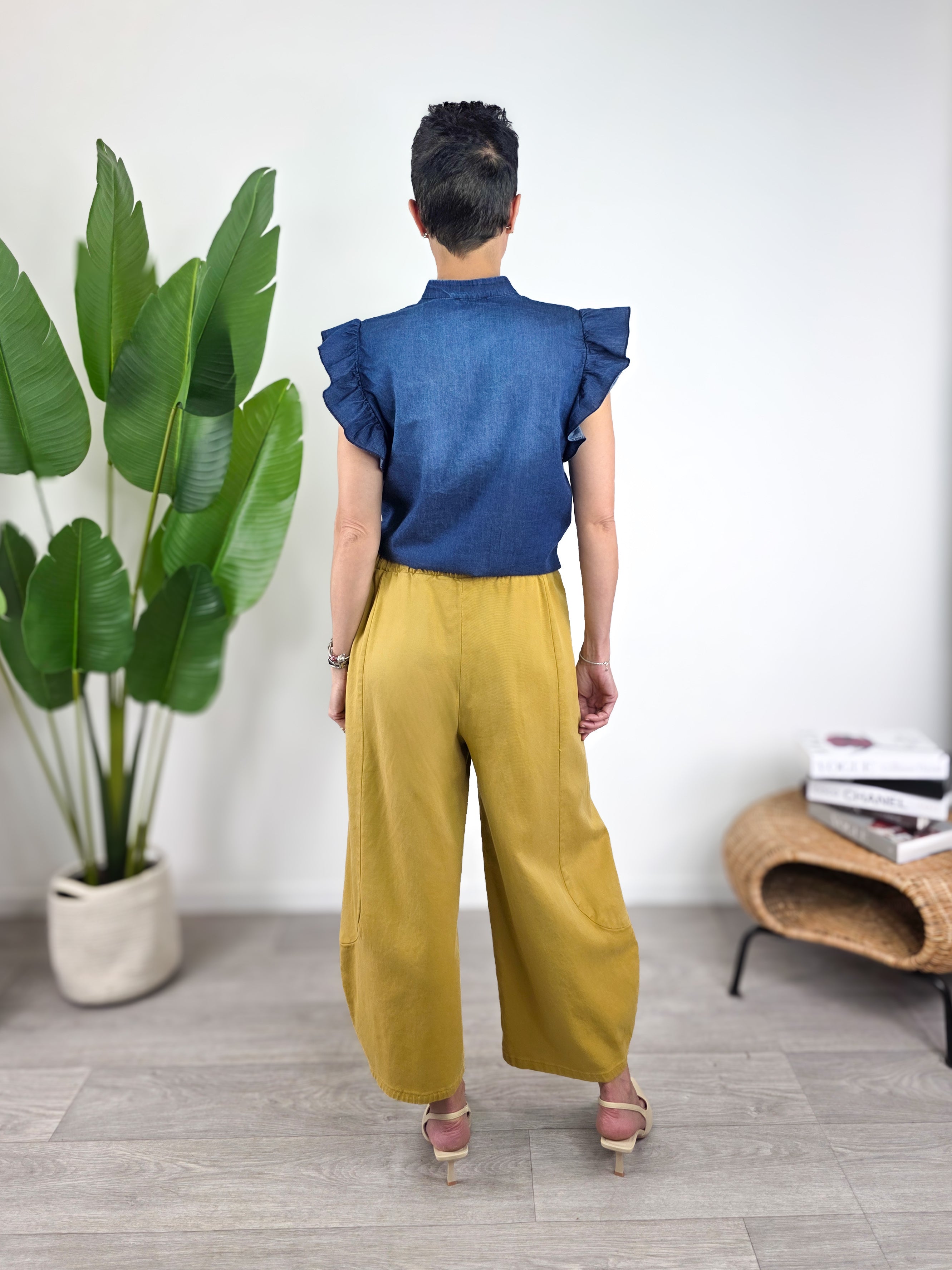 Camicetta Susy Mix in chambray blu con collo coreana abbinata a pantalone senape, look casual elegante. Visione posteriore 